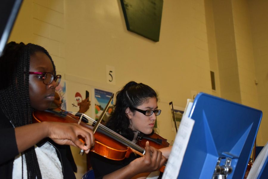 Eighth graders Margaret Owusu and Marjorie Juarez play violin as part of the strings program.