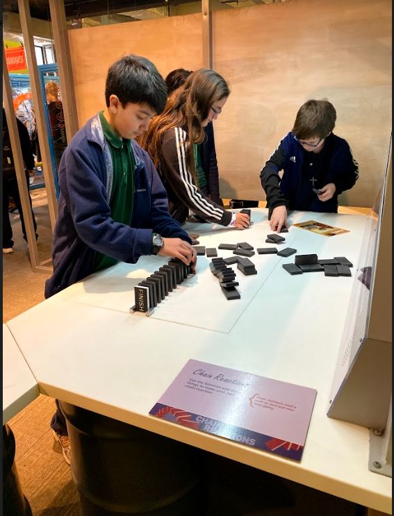Ethan Mandap, Faith Kennedy, and Thomas Rotenbury explore the concepts of physics with dominoes at The Franklin Institute.